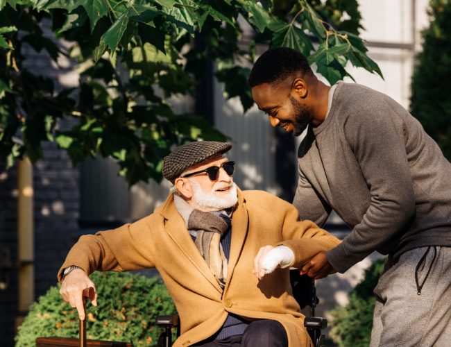 Man providing assistance with daily personal activities to old aged man